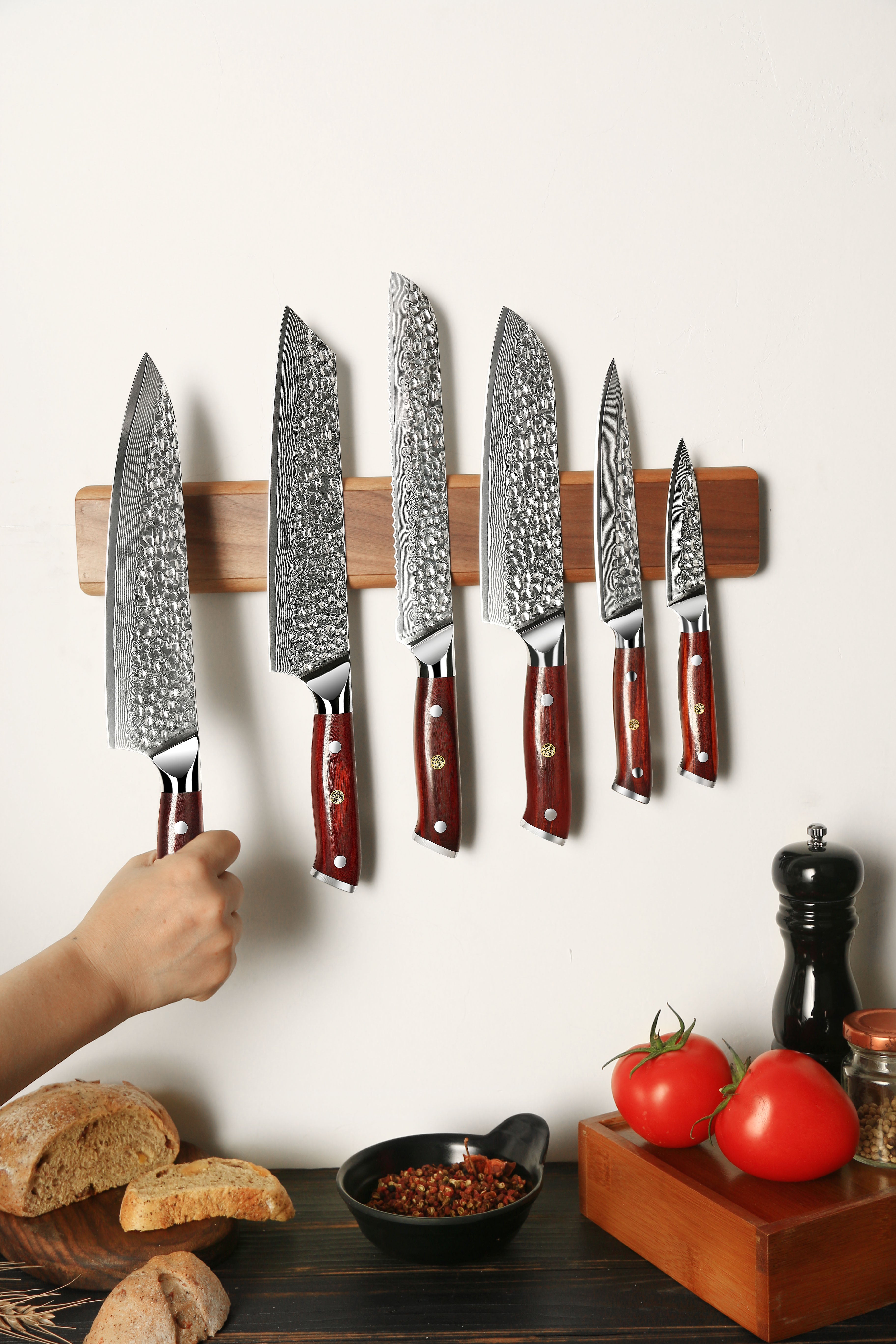 Set of knives on a magnetic wall strip with a kitchen setting below