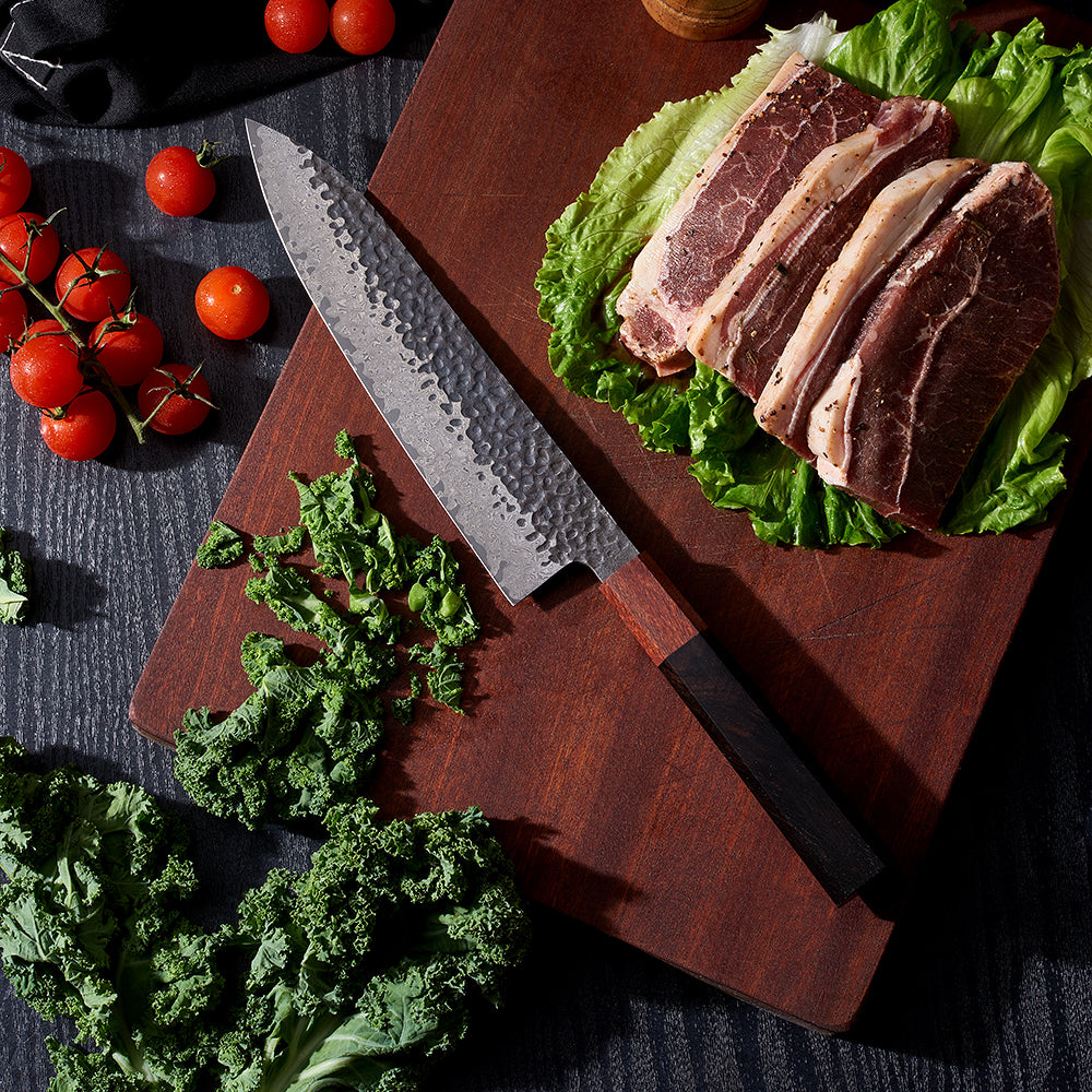 Japonský šéfkuchařský nůž s damaškovým a bambusovým povrchem v blízkosti steaků