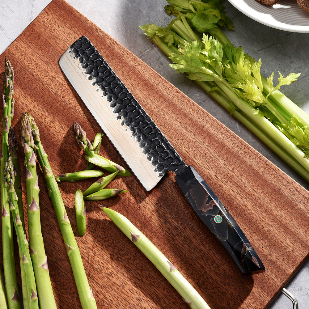 Wooden cutting board with green asparagus and a Premium Japanese Knife for Vegetables with damascus and copper blade on a gray surface