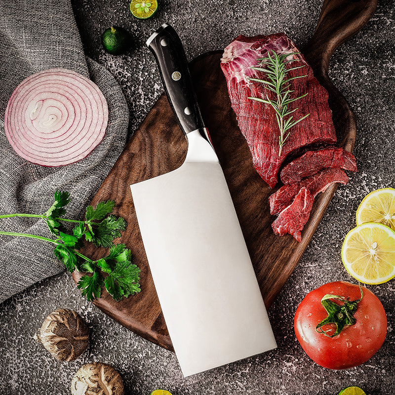 Raw beef on a wooden cutting board with a german steel cleaver, surrounded by vegetables on a dark surface.