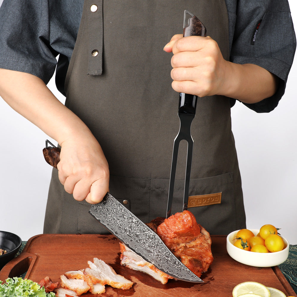 A person wearing a dark brown apron slices roasted meat on a wooden cutting board with a patterned steel cleaver and a black meat fork. Small bowls of green onions and yellow citrus are visible on the side.