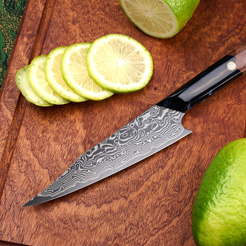 A kitchen knife with a Damascus steel pattern blade and a black handle, resting on a wooden cutting board surrounded by sliced and whole limes.